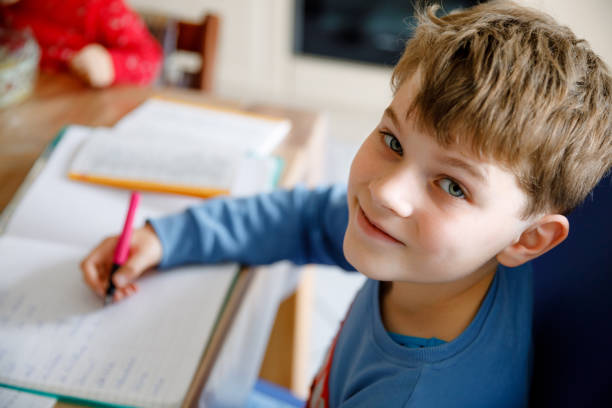 istock Hard-working happy school kid boy making homework during quarantine time from corona pandemic disease. Healthy child writing with pen, staying at home. Homeschooling concept 1464721451