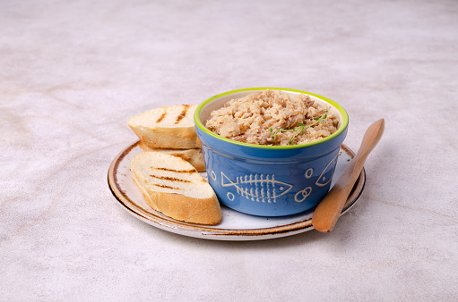 Fish pate with bread in a ceramic dish on a light background. Selective focus.