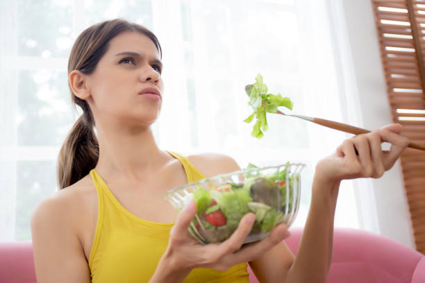 istock Young caucasian woman sitting on sofa eating vegetable salad while feeling dislike and expression disgusted, woman emotion frustrated with anorexia vegetarian and hate, nutrition food concept. 1464723113