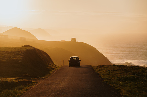 Silhouette of a car on a road in a beautiful landscape at sunset