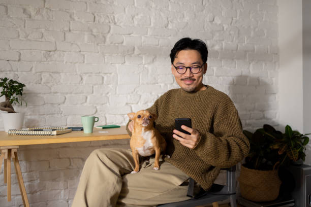 ragazzo cinese fresco a casa con il suo cane - cool business looking at camera posing foto e immagini stock