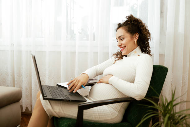 istock Pregnant woman using laptop at home 1464729073