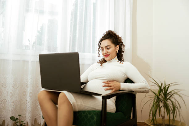istock Pregnant woman using laptop at home 1464729076