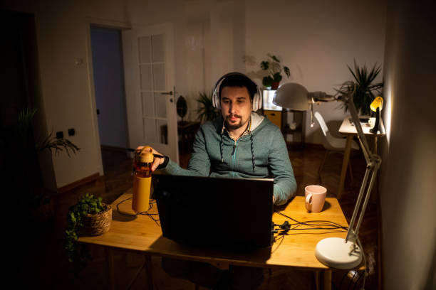 istock Male student e-learning on laptop late at night 1464729307