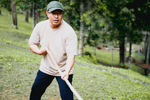 Business team and creative team playing tug-of-war in the forest