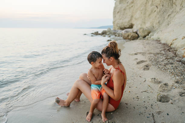 Photo of a little boy and his mother taking a moment for themselves  and ending busy week on a local beach