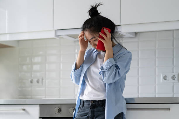 giovane donna asiatica depressa triste a casa che parla al telefono, donna sconvolta che chiama psicologo - telephone worried one person discussion foto e immagini stock