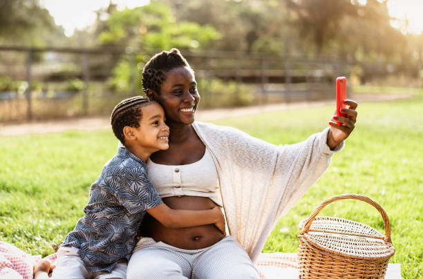 istock Happy African pregnant mother taking selfie with his son while doing a picnic during weekend in public park - Maternity and parents lifestyle concept 1464734725