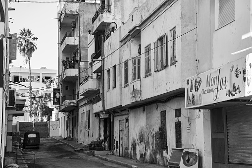 Sousse, Tunisia, February 7, 2023: Side street in a Tunisian city with apartment buildings and weathered facades with paint peeling off, black and white