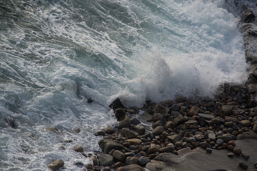 Powerful sea wave breaks on a rocky shore