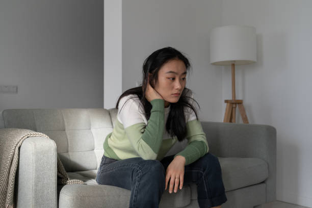 istock Sad depressive Korean woman sitting on sofa thinking about failure, having psychological problems 1464738948