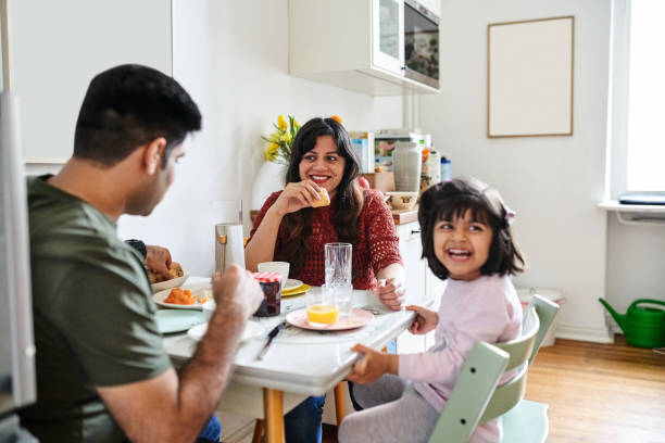 istock Happy family eating breakfast at dining table in kitchen 1464739821