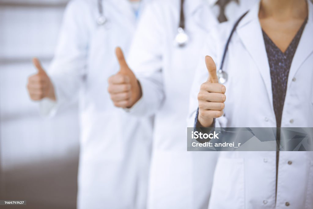 Doctors standing as a team with thumbs up in clinic and ready to help patients. Medical help, insurance and medicine concept Doctors standing as a team with thumbs up in clinic and ready to help patients. Medical help, insurance and medicine concept. Thumbs Up Stock Photo