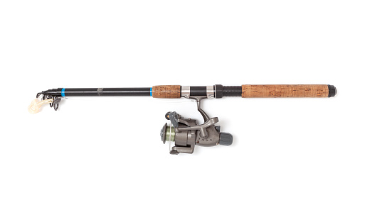 A folded telescopic spinning rod lies on a white background. A gray inertialess reel is fixed on it with a fishing line and a twister