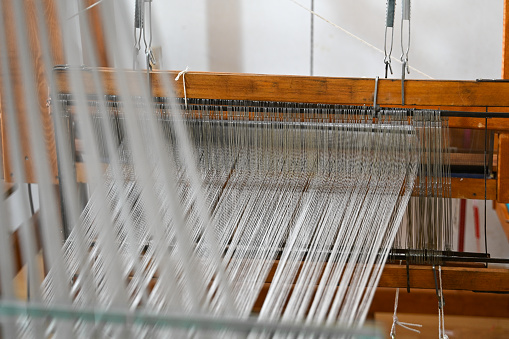 Traditional wooden loom with white weaving yarns