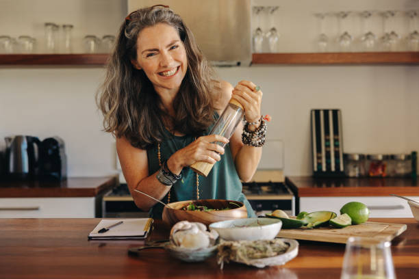 Cheerful senior woman following a healthy vegan recipe at home stock photo