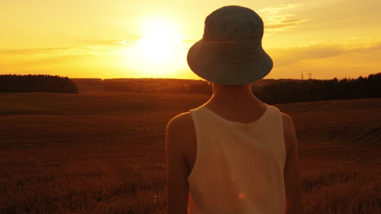 teen alone boy in the field at sunset looking into the distance in summer day, back view, boy in the Mars