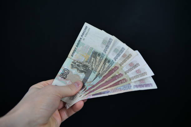 istock Russian ruble banknotes held in hand in front of a black background 1464745973