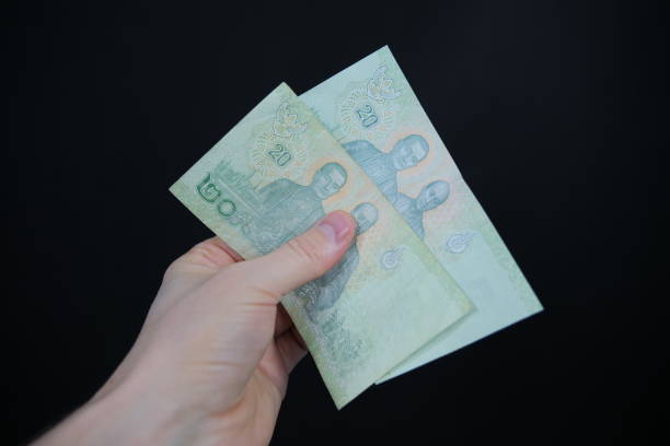istock Thai baht banknotes held in hand in front of a black background 1464746029