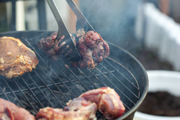 Cooking different meat on barbecue. Grilled and roasted lamb steaks on bbq. Take one piece with grill tongs. outdoors