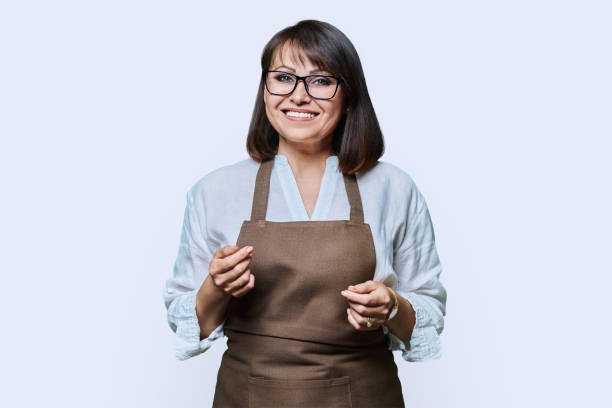 istock Confident middle aged woman in apron looking at camera on white background 1464751867