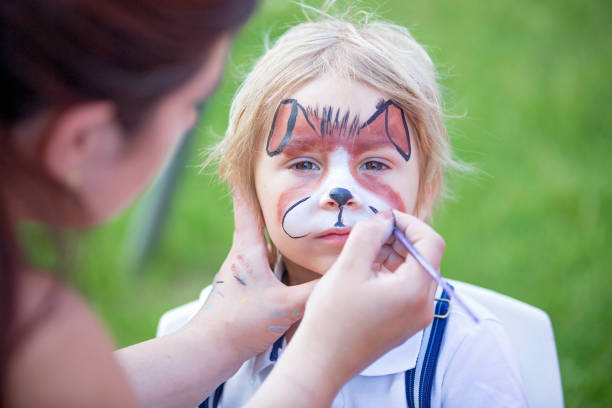 petit tout-petit garçon, enfant avec le visage peint comme un chien, jouant avec un chien de compagnie dans le jardin - face paint child animal little boys photos et images de collection