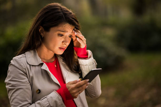 istock Worried young woman using phone outdoors on autumn day. 1464755055