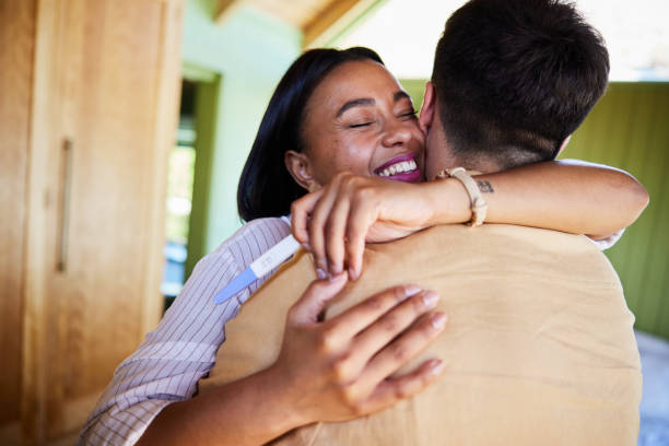 istock Ecstatic woman hugging her husband after a positive home pregnancy test 1464756473