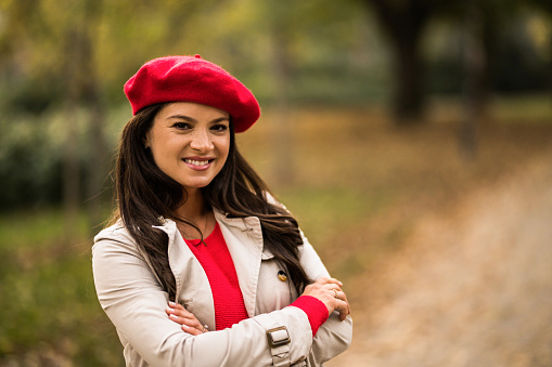 Portrait of young woman enjoying an autumn walk in the park and looking at the camera.