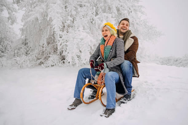 istock Couple sits on a sled and slides down the hill 1464756955