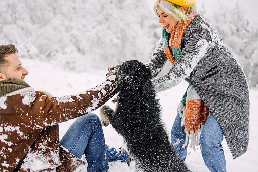 Loving couple is enjoying the snow with their dog