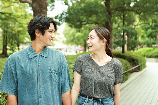 Happy young Asian married couple looking each other in the park.