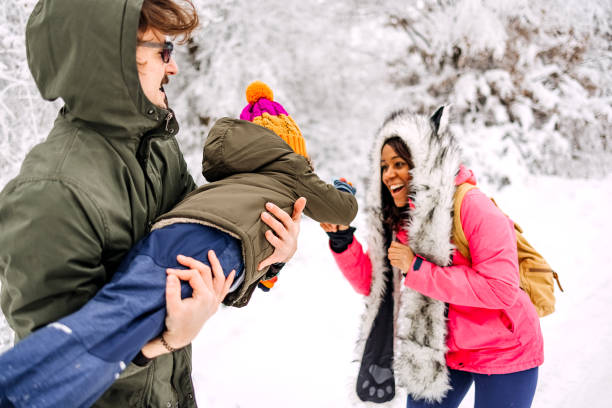 Cheerful young family, being playful outdoors in nature covered in snow