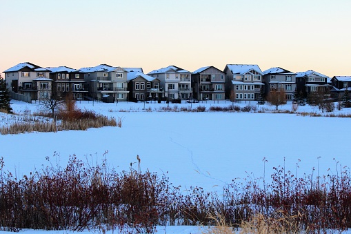 A view of a beautiful lake, or retention pond, surrounded by reeds and homes in the winter  evening  in winter North Edmonton, in the neighbourhood of Crystalina Nera.