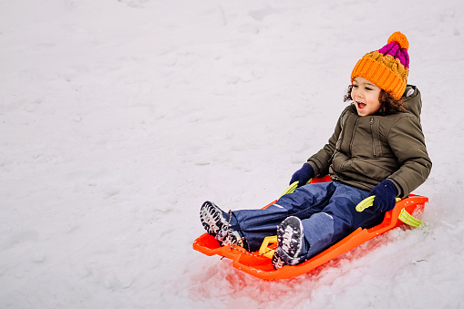 Little boy  slide down from snow slope sitting in one slide.
