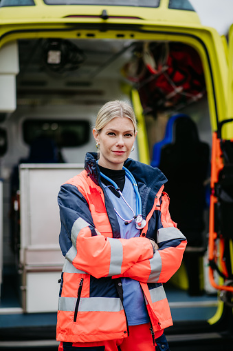 Portrait of a young woman doctor standing in front of ambulance car.