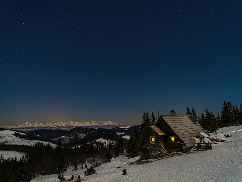 Mountain hut Andrejcova in Low Tatras Slovakia under a starry sky during winter snow window lights forest