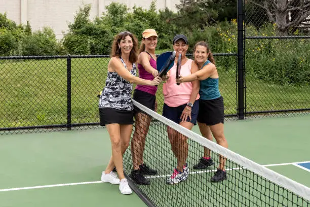Photo of Four Female Pickleball Players Touch Paddles