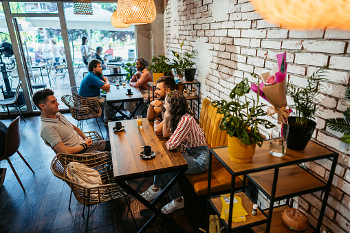 Young group of friends relaxing in a café, drinking juice and coffee.