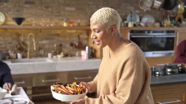 Smiling woman bringing roasted vegetables to holiday table