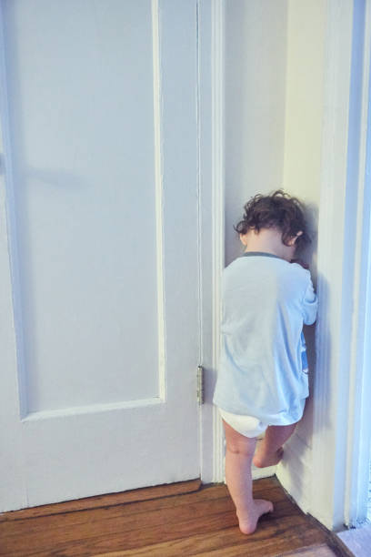 クローゼットのドアのそばに立っている幼児 - corner child hiding looking ストックフォトと画像