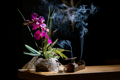 burning incense and pink flower on the table