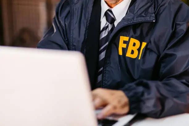 Handsome mature FBI agent using laptop in the office late at night.