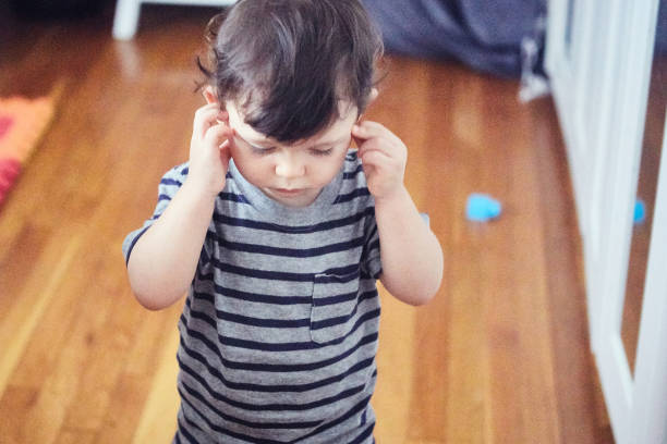 View of a toddler with hands covering ears