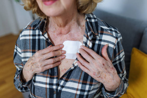 Hormone threatment patches A close-up of a senior Caucasian woman applying a hormone patch to her chest. transdermally stock pictures, royalty-free photos & images