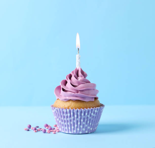istock Delicious birthday cupcake with burning candle and sprinkles on light blue background 1464770141