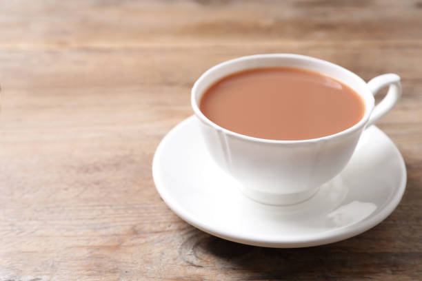 istock Delicious tea with milk in white cup on wooden table 1464770228