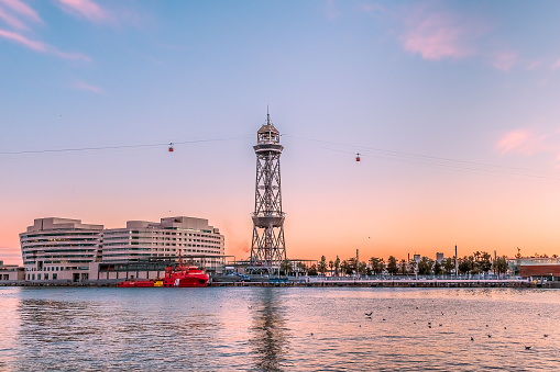 Pink sunset in the port of Barcelona and the steel Torre Jaume I tower of the Port Vell Aerial Tramway on the horizon, Spain