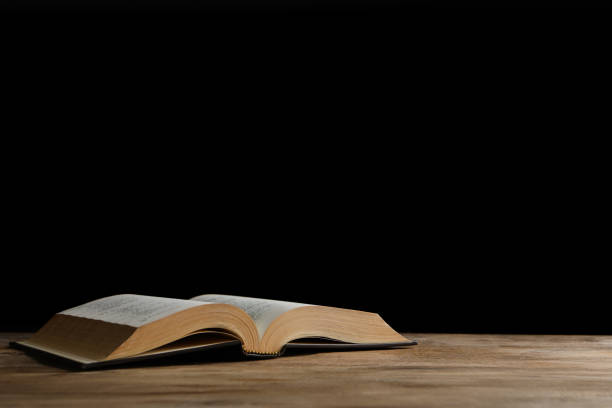 istock Open Bible on wooden table against black background, space for text. Christian religious book 1464771614