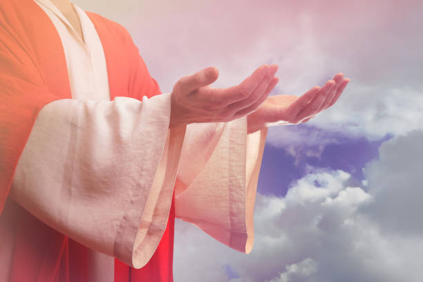 istock Jesus Christ reaching out his hands and praying against blue sky 1464772314